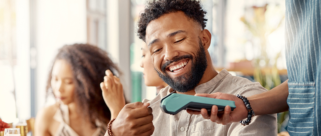 Man using credit card to purchase meal at restaurant