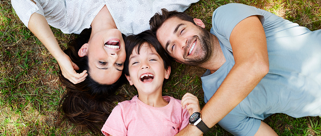 Young family bonding and looking at clouds in grass