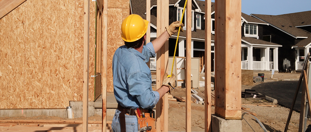 Contractor taking measurements at construction site in subdivision