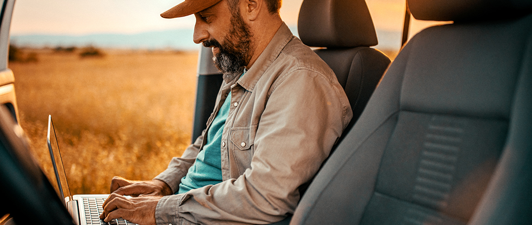 Farmer working on laptop remotely in field