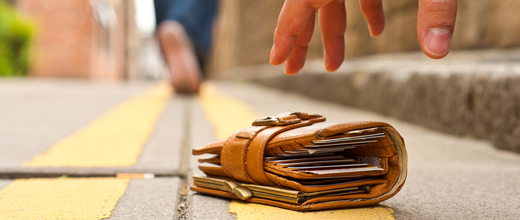 Stranger finding a lost wallet with cash and credit cards in the middle of a street