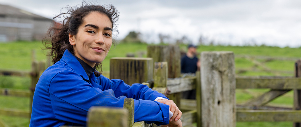 Woman leaning on fence at a farm