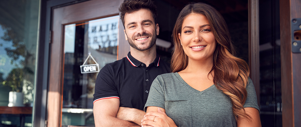 Small business owners proudly standing by entrance